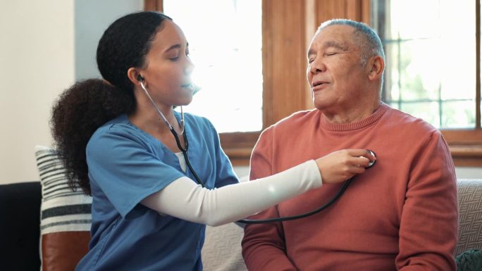 妇女、护士在客厅沙发上检查老人的心跳。女性、医生或医疗护理人员监测老年患者的呼吸或在家呼吸