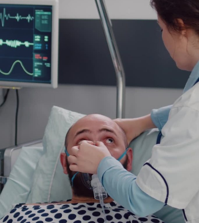 垂直视频:病人躺在床上休息，女医生戴上氧气面罩