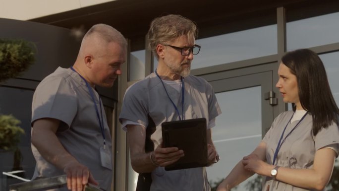 穿着制服的医生站在医院门口，使用数码平板电脑