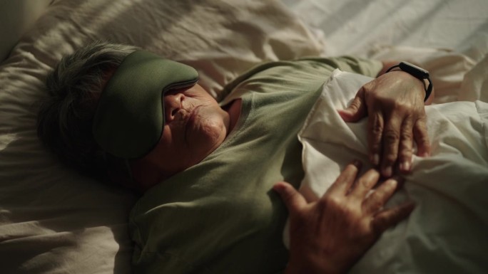 老年妇女戴着眼罩睡觉。