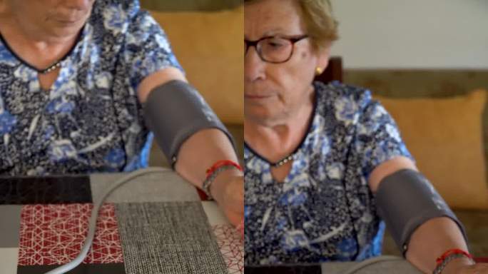 一位老妇人在家里用数字监测仪测量血压。