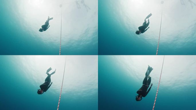 自由潜水员沿着绳索运动。一名女子自由潜水者在开阔的海面上沿着绳索训练，然后下潜到深海