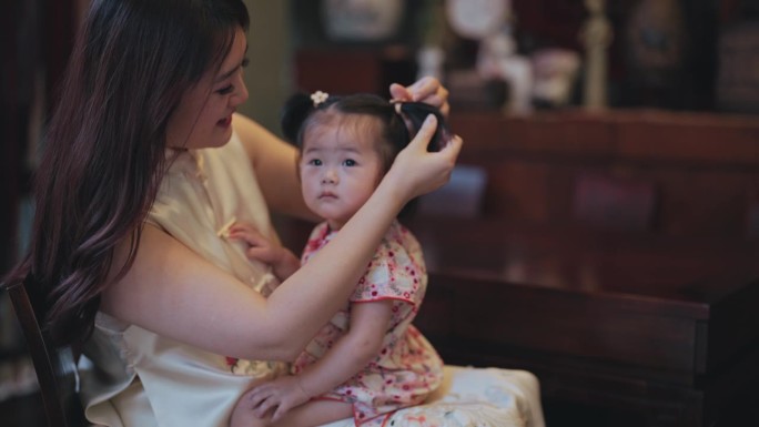 中国新年妈妈在客厅给女婴扎头发