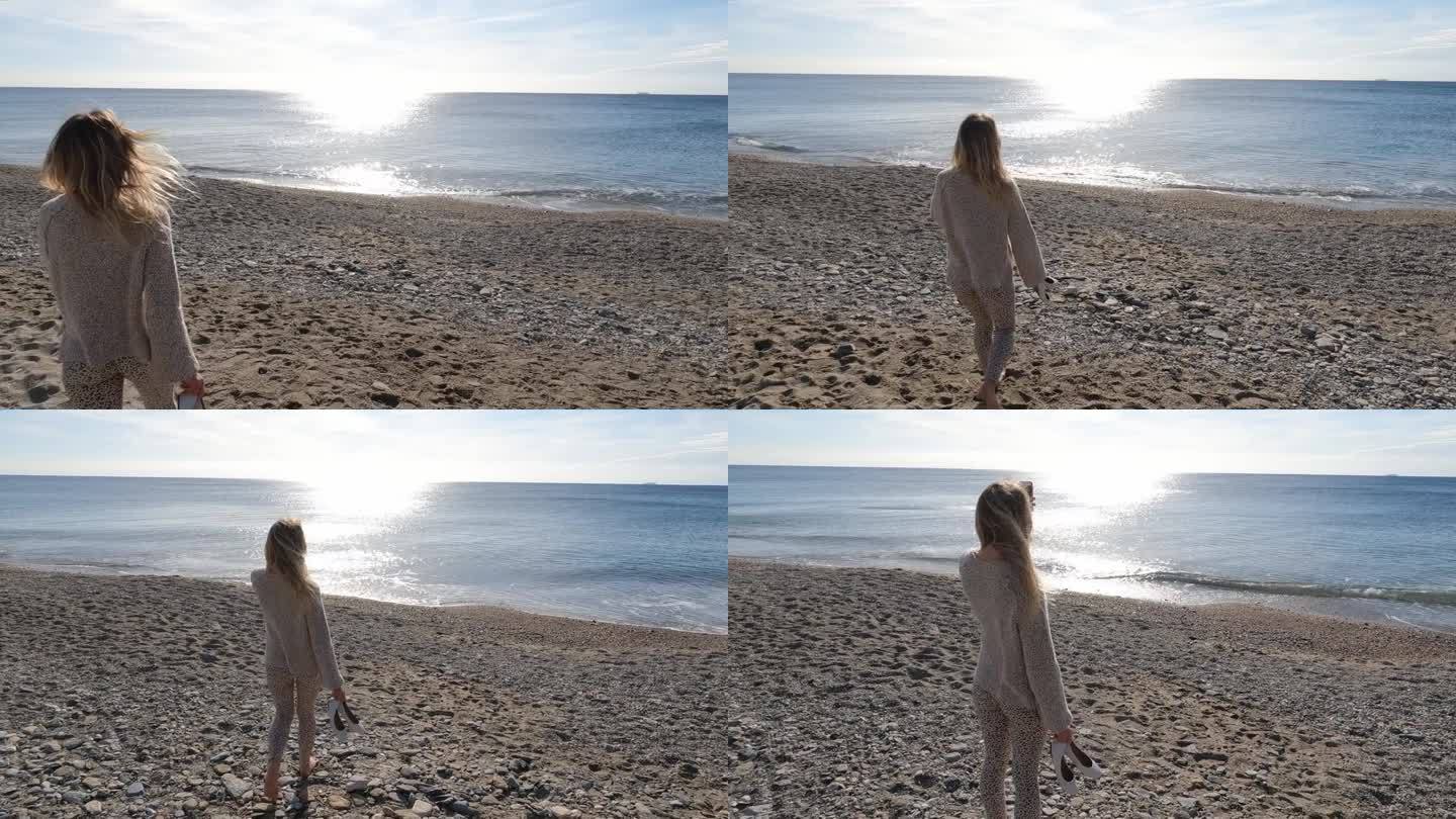 年轻女子沿着海滩走向大海