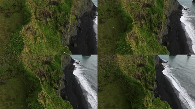 陡峭的悬崖揭示了冰岛南海岸著名的雷尼斯加拉黑沙滩。无人机航拍