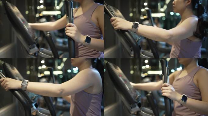 女性左臂在健身房里的椭圆机上剧烈运动的剪影。