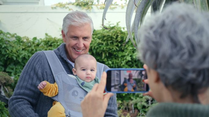 宝宝，手机和照片的快乐祖父母一起在户外，微笑和亲情在家里。孩子，照片和老夫妇在后院的花园为家庭连接，