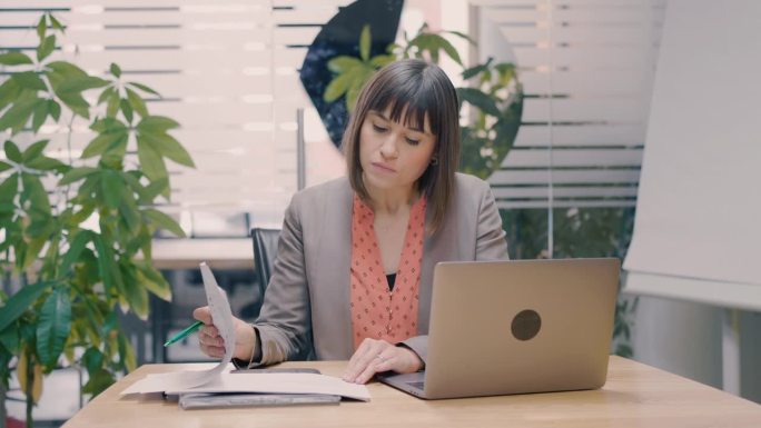 现代办公室里用笔记本电脑工作的女商人