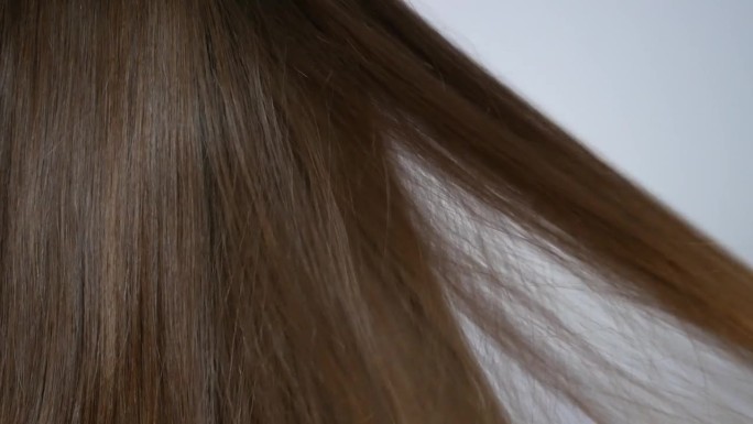 一个黑发女人用木梳子梳理她美丽的长发的特写
