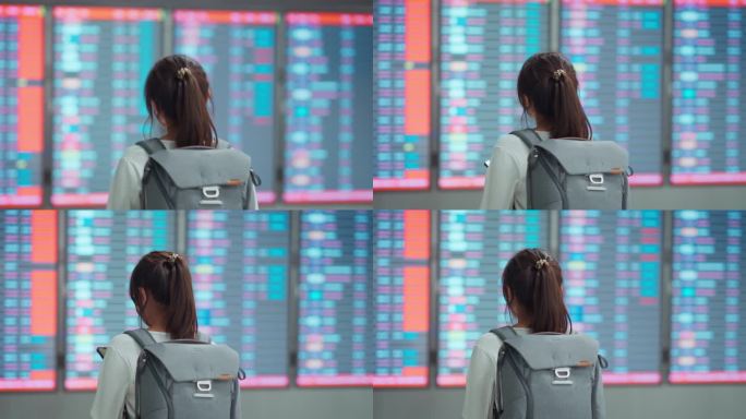 快乐的亚洲女旅客在机场候机楼检票柜台前查看航班时刻表。