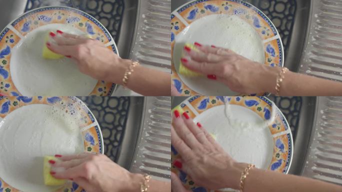 女人用清洁剂和海绵洗脏盘子。