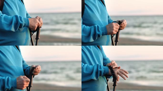 无法辨认的老人手斯堪的纳维亚手杖在日落海滩天空地平线的特写