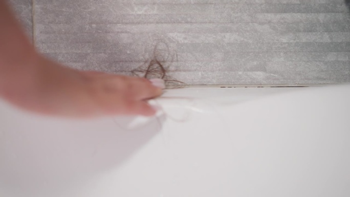 用手收集浴室热水浴缸墙壁上掉落的头发