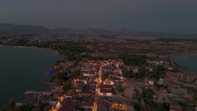 土耳其，边老城照亮沿海住宅鸟瞰图在日落时飞过建筑物屋顶