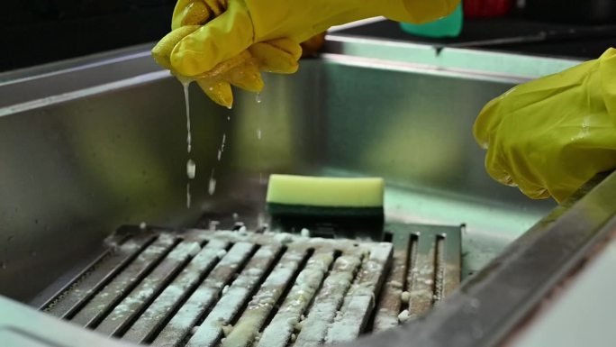 家政人员将酸橙汁挤在沾污的灶具罩过滤器表面进行清洁。