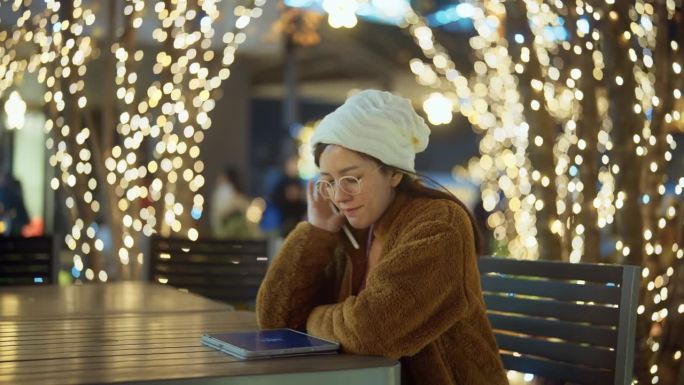 一名亚洲妇女坐在那里，用平板电脑搜索日本夜市的著名餐厅