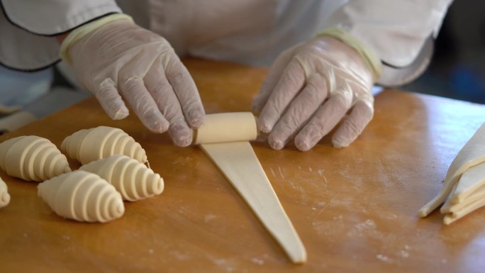 一位法国糕点师在桌上铺开牛角面包面团