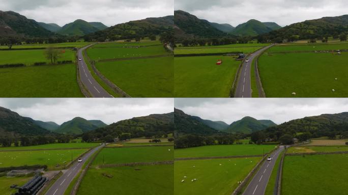 白色的电动汽车行驶在乡村公路上，穿过绿色的草地，背景是史诗般的山脉。