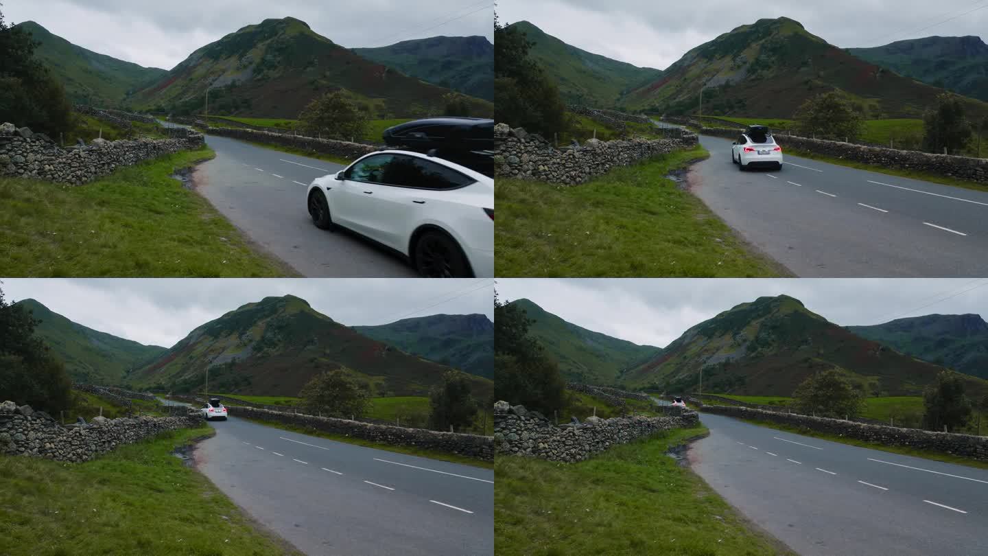 一辆白色的电动汽车行驶在英格兰壮丽的山间小路上。