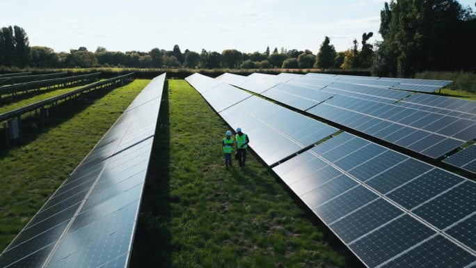 无人机拍摄的工程师在现场检查太阳能电池板产生可再生能源
