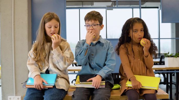 小学生坐在桌子旁吃苹果