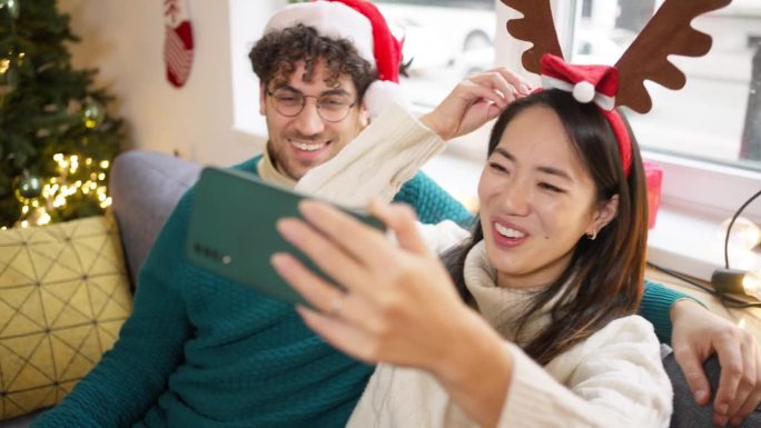 多种族夫妇在视频通话中挥手致意，同时在家中享受圣诞节和新年的气氛