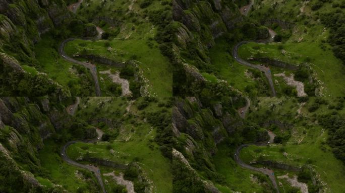 无人机在饱和的绿色悬崖和蜿蜒的切达峡谷公路上升起