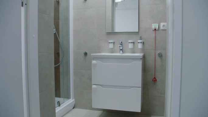 在明亮的浴室中间，白色的水槽上面有镜子