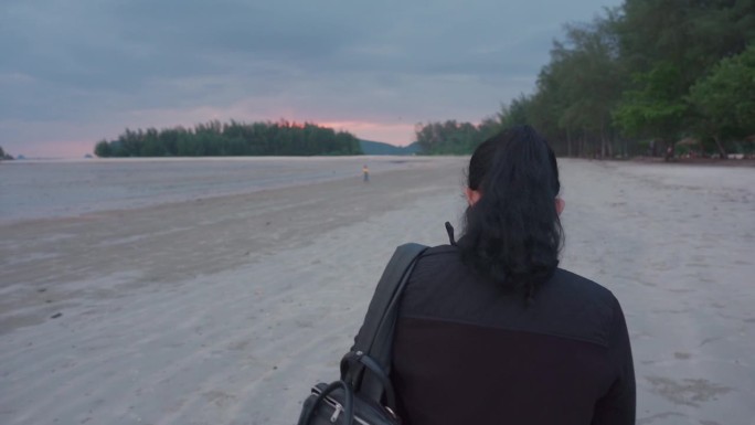 傍晚时分，一位亚洲老妇人在海边散步，欣赏着田园般的海滨风光和日落，享受着放松的时刻。无忧无虑的亚洲女
