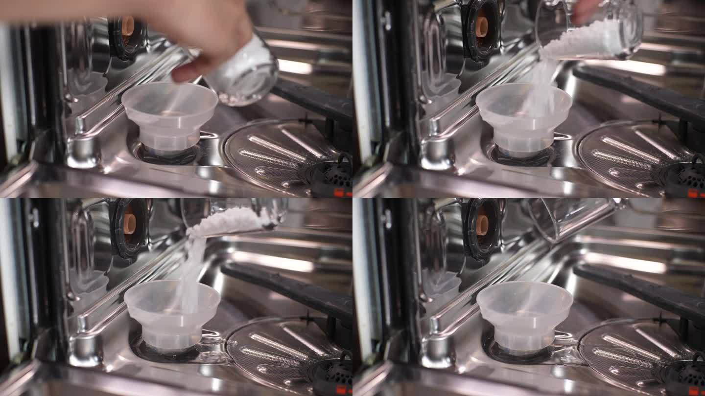 一个不知名的人用漏斗将盐粒倒入洗碗机孔中软化硬水。洗衣机保养的概念。