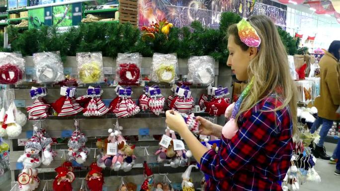 一位年轻的女士在商店里为圣诞树挑选新年玩具