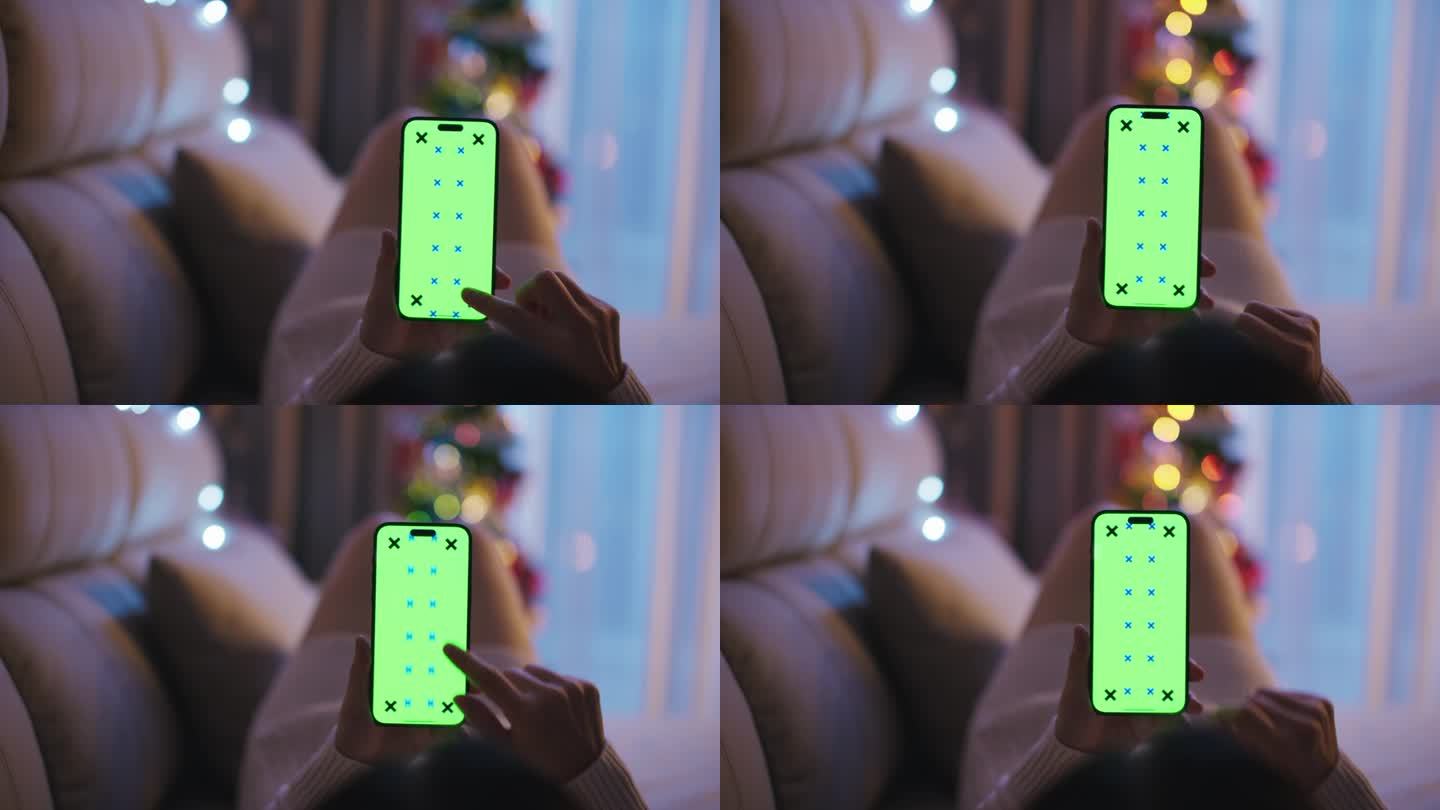 女人手拿绿屏智能手机舒适的家近距离。