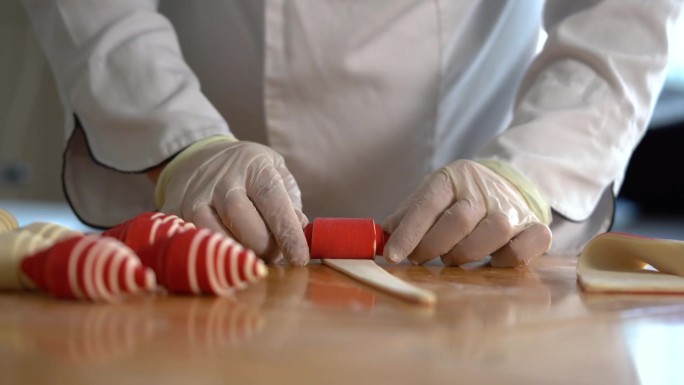 一位法国糕点师在桌子上卷红羊角面包面团