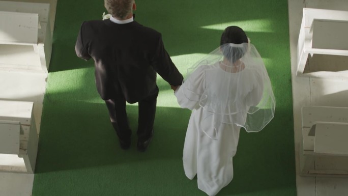新人走在绿地毯上走向婚礼祭坛的俯视图