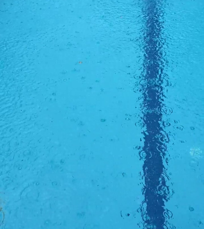 大雨打在泳池表面。雨滴在水面上产生气泡