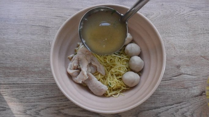 用银勺煮中国黄蛋面，配肉片和球，清汤