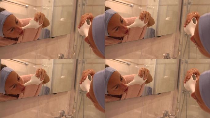 一名妇女正在使用天然生理盐水冲洗鼻子。洗鼻壶