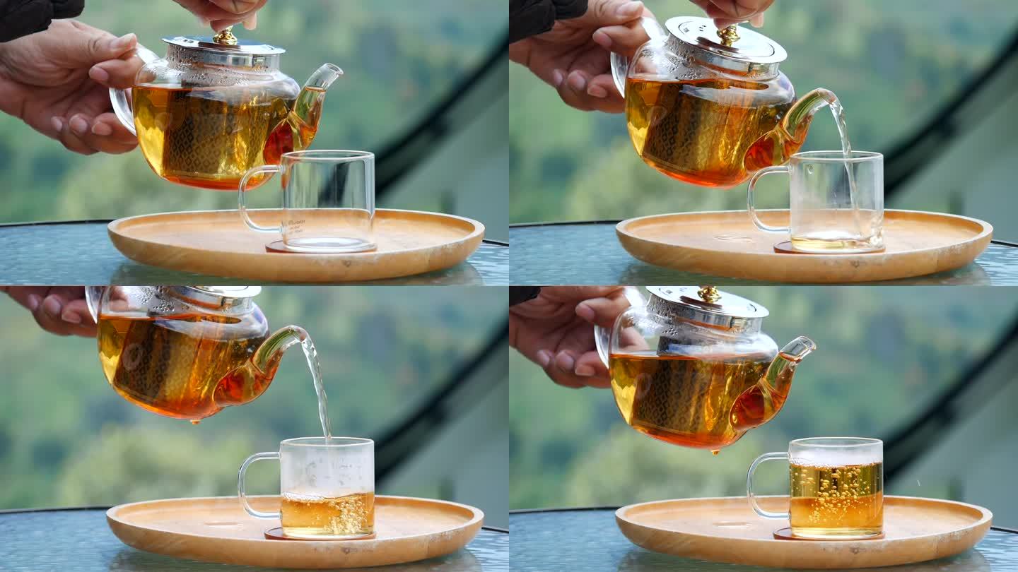 木托盘上的玻璃茶壶，手从茶壶里倒茶