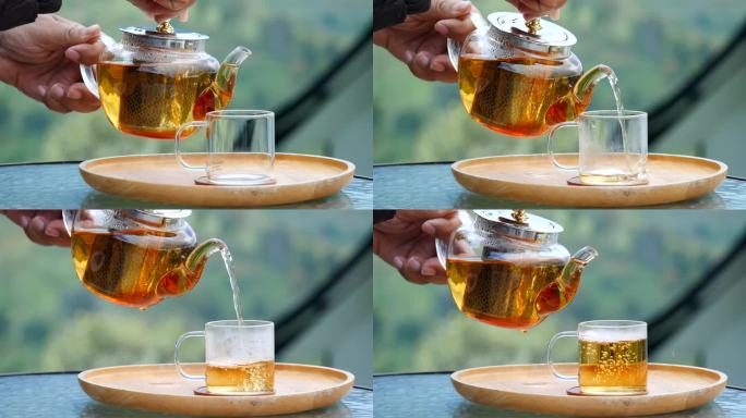 木托盘上的玻璃茶壶，手从茶壶里倒茶