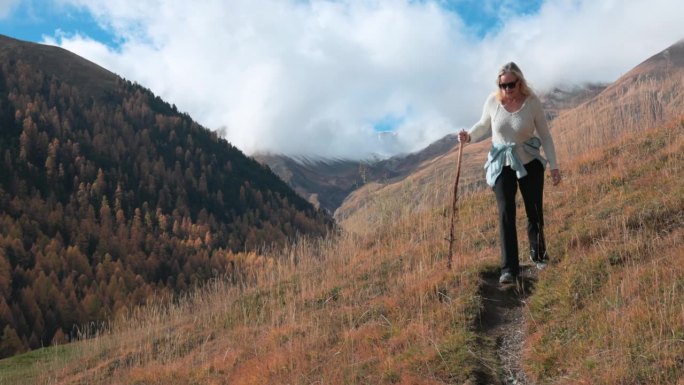 成熟的女性徒步旅行者探索高山山坡，秋天