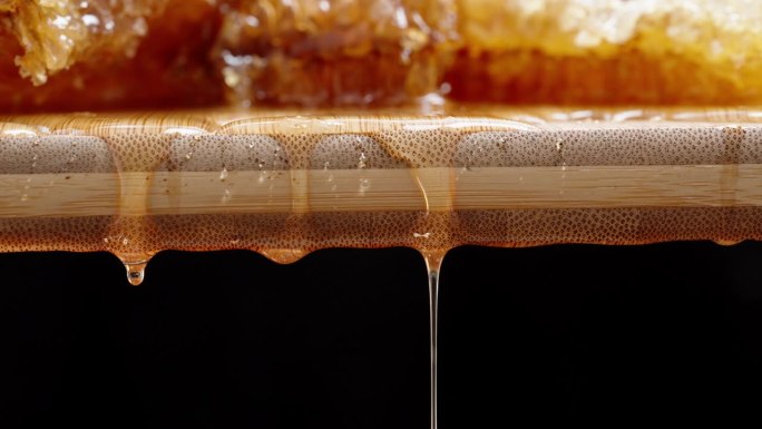 天然蜂蜜在一块木板上的蜂巢，从上面滴下蜂蜜。多莉滑块极端特写。