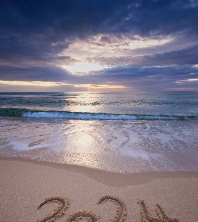 清晨在海边，文字新年2024在海沙和沙滩垂直视频