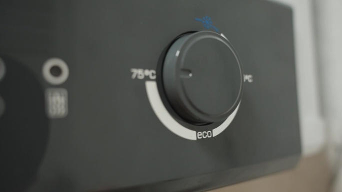 男手将热水器温度调节器从ECO模式调节到最高温度。