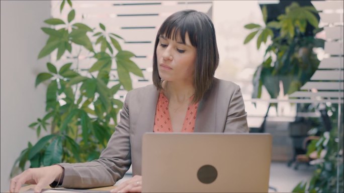现代办公室里用笔记本电脑工作的女商人