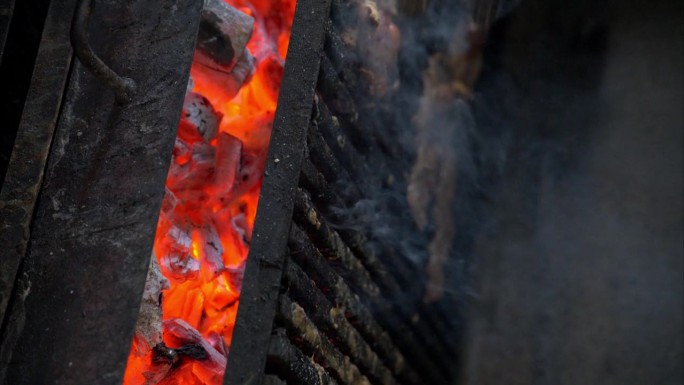 餐馆里用烧得通红的木炭在烤架上烤牛排的慢动作。垂直拍摄