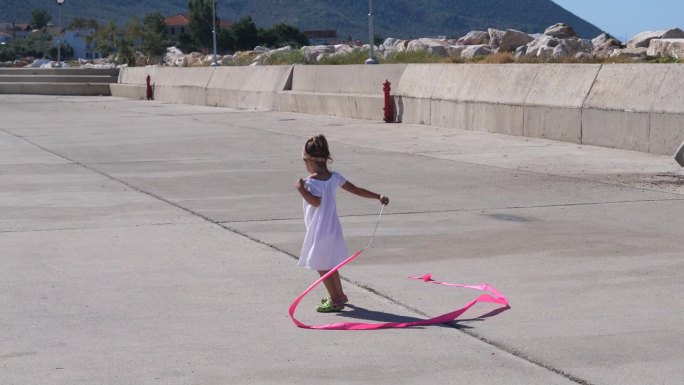 小女孩在夏日休闲时玩得很开心，用一条体操粉丝带