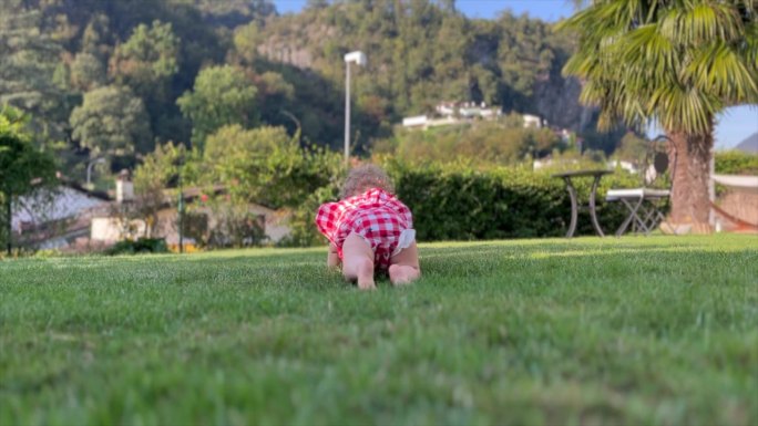 小女孩正在学习如何在花园的绿草地上爬行
