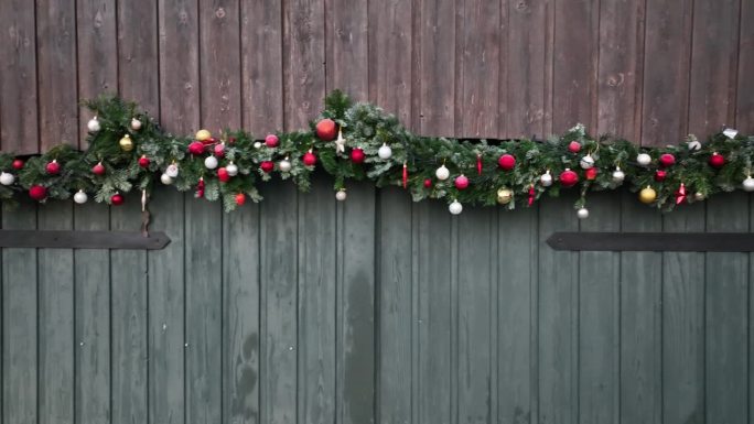 用圣诞花环装饰的轻型祖母绿谷仓门的航拍镜头。谷仓里有节日装饰，如星星、球和装饰圣诞树的装饰品。