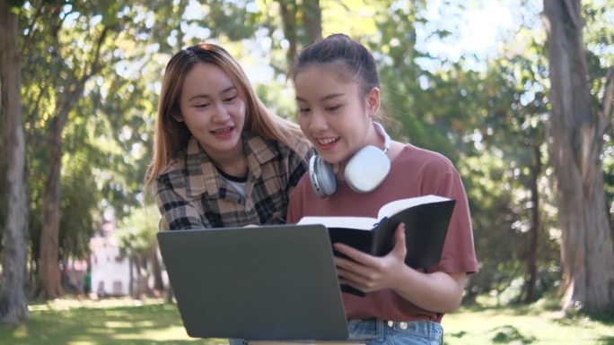 两名女学生坐在大学校园的草地上一起工作和学习考试