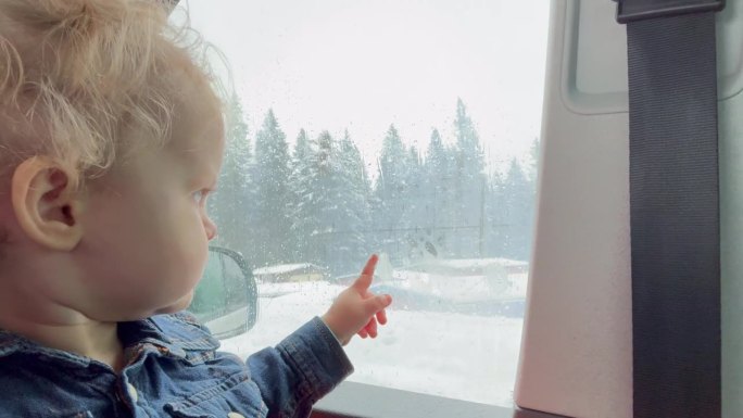 宝宝看着窗外下雪的天气和森林